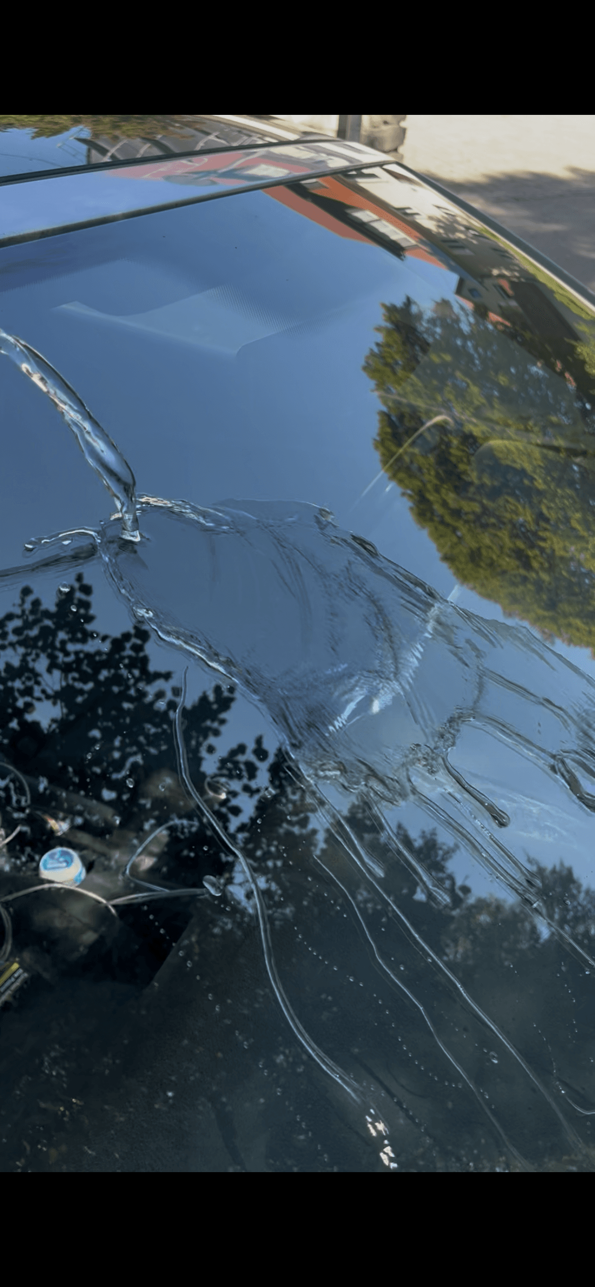 Abperlende Wassertropfen auf einer geschützten dunklen Lackfläche